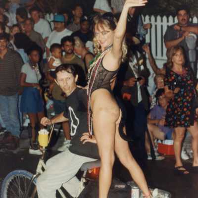 Unknown woman dressed up on the back of bike.