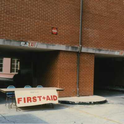 A brick unknown building with a first aid table set up.
