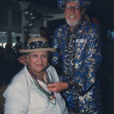 Unknown man dressed up putting beads around an unknown ladies neck.