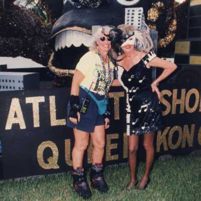 Two unknown woman dressed up standing next to a float.