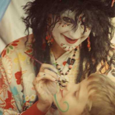 Unknown person dressed up painting a child's face.