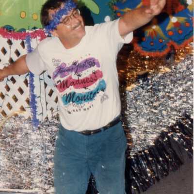 A Fantasy Fest parade monitor standing next to a float.