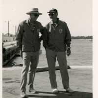 2 Unknown men standing near a pier