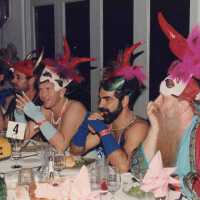 Five unknown men dressed up sitting at a table.