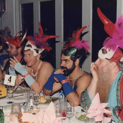 Five unknown men dressed up sitting at a table.