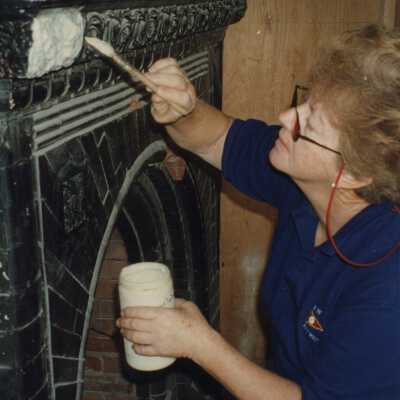 An unknown woman painting one of the fireplaces.