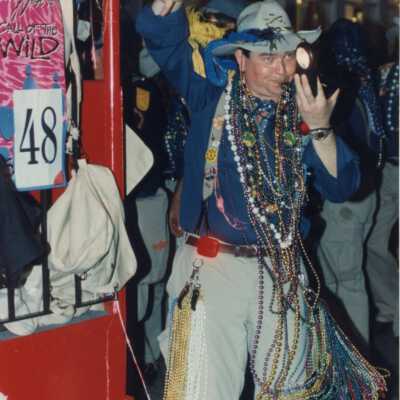 Unknown man with many beads attached to him standing next to float number 48.