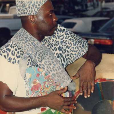 Unknown man dressed up holding some sort of instrument.