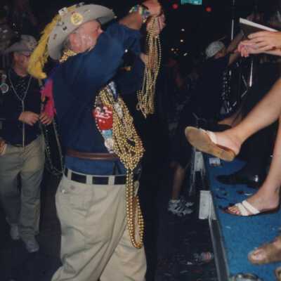 Unknown man dressed up giving someone beads.
