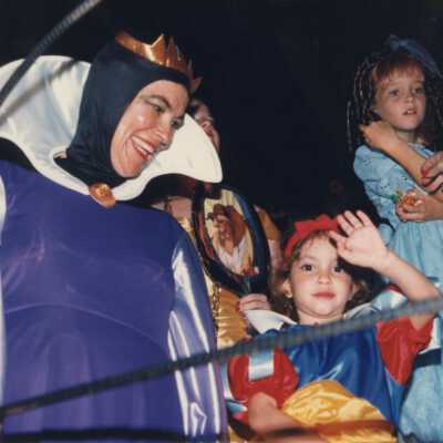 An unknown woman dressed up with two unknown kids dressed up.