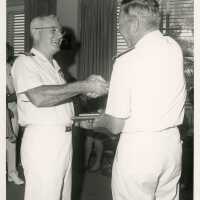 2 Men in uniform shaking hands and receiving a plaque