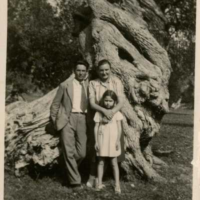 An unknown family standing near a tree
