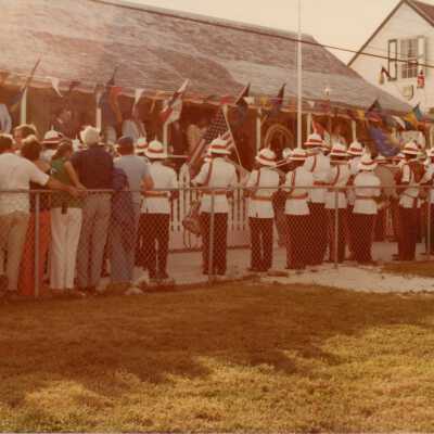 An unknown group of people standing against a fence