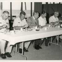 A group of men eating at a table, a few in uniform