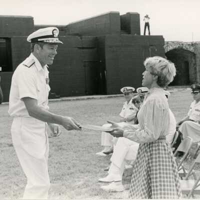An unknown man in uniform handing a woman an award