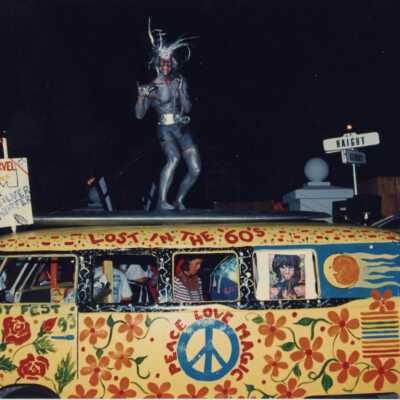 Unknown people in and outside of a painted van that reads Peace, Love, and, Magic.