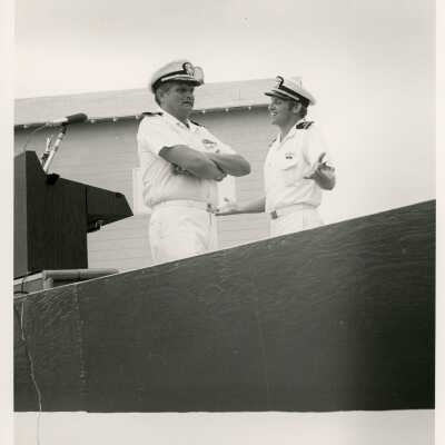 2 Men in uniform talking next to a podium