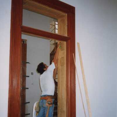 An unknown man working on the wood work on one of the doorways.