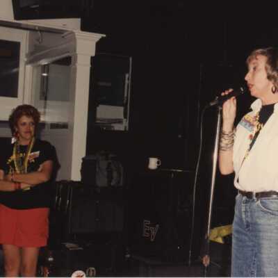 Unknown woman on a stage talking to a group of people.