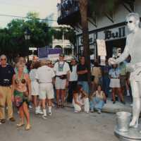 A group of unknown people standing around the Silver man in front of The Bull.