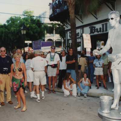 A group of unknown people standing around the Silver man in front of The Bull.