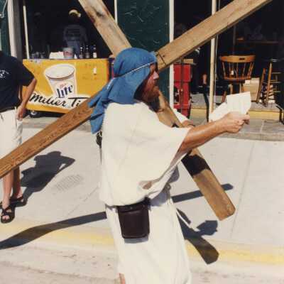 Unknown man dressed up holding a cross.