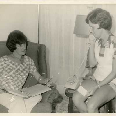Woman in an office, one is using the phone