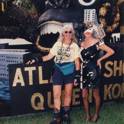 Two unknown woman dressed up standing next to a float.