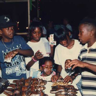 Unknown kids looking at items that are at a Goombay booth.