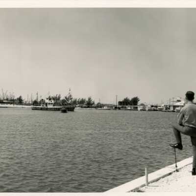 A view of the ocean with a ship and an unknown man in uniform standing on the pier