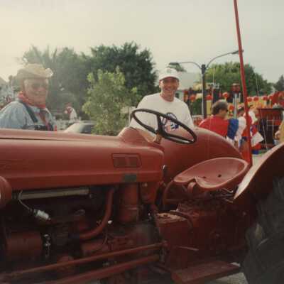 Two unknown men standing near a tractor.