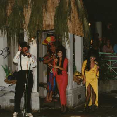 Unknown people dressed up on a stage singing.