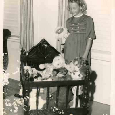 An unknown child looking down at stuffed animals in a cradle