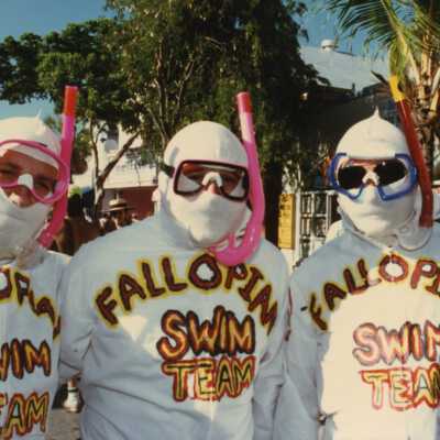 Three unknown men dressed up, shirts read Fallopian swim team.