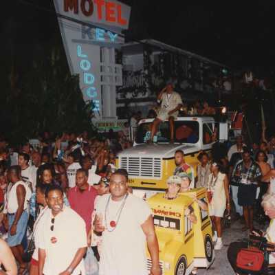 A huge group of unknown people walking in the street next to a float.