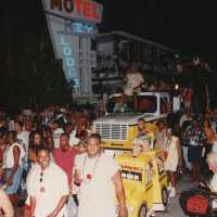 A huge group of unknown people walking in the street next to a float.