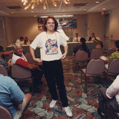 Unknown man showing off a Fantasy Fest t shirt at the meeting.