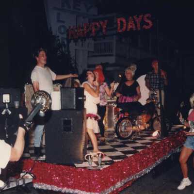 Unknown people dressed up on a float that reads Happy Days.