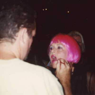 Unknown man putting make up on an unknown woman who is dressed up.