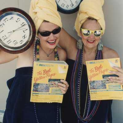 Two unknown woman dressed up holding clocks and phone books.