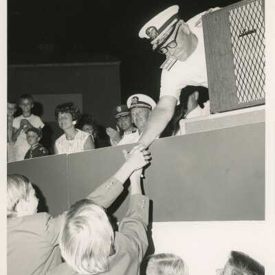 Unknown kids shaking hands with a man in uniform.