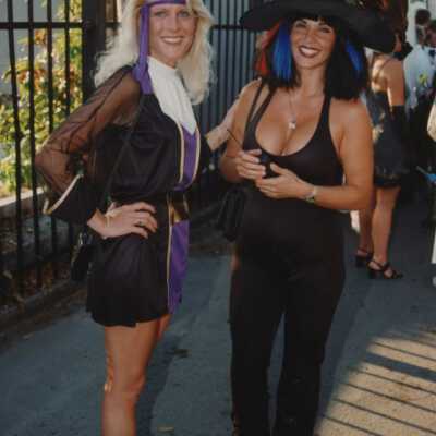 Two unknown woman dressed up standing next to the cemetery.