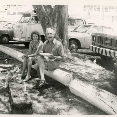 An unknown male and female eating while sitting on a log