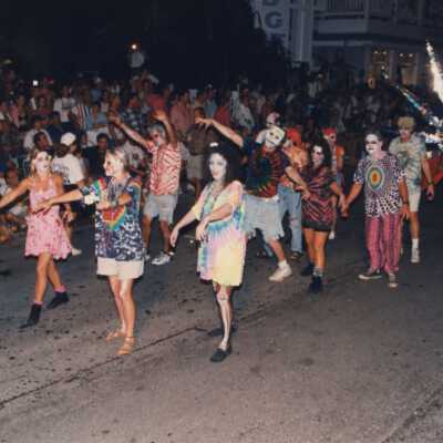 Unknown people dressed up walking down the street in a parade.