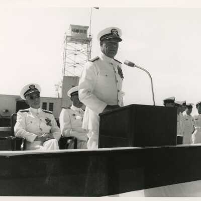 Men in uniform, one standing at the podium