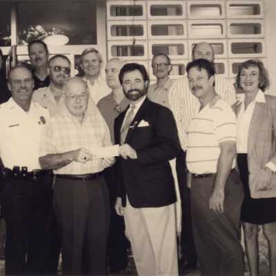 Unknown group of people standing in front of the City Hall. One is accepting a check.