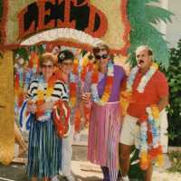Four unknown people dressed up standing in front of a float.