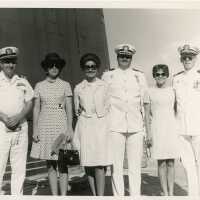 A group of unknown people some in uniform on a ship.