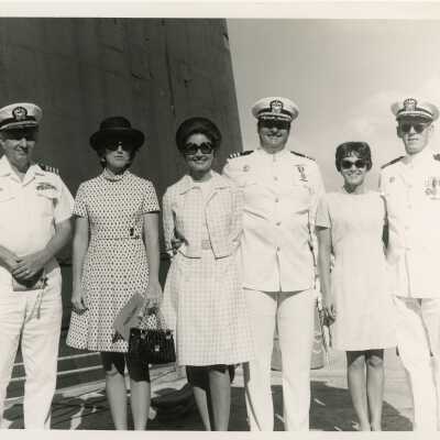 A group of unknown people some in uniform on a ship.