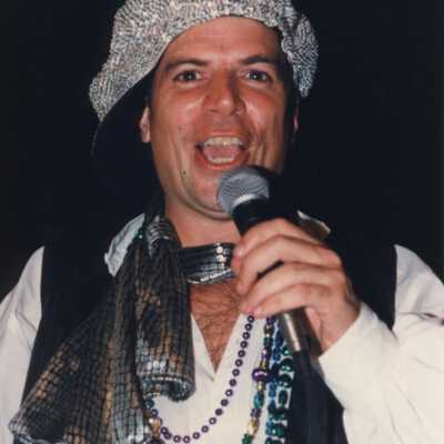 Unknown man dressed up talking in a microphone.